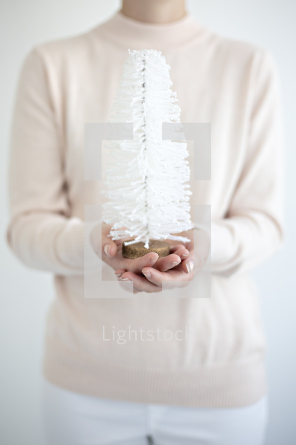 a woman holding a bottle brush Christmas tree