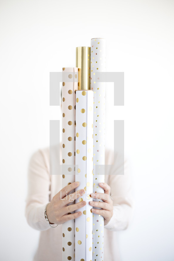 a woman holding rolls of wrapping paper 