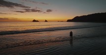 Silhouette Of Couple Standing At The Beach During Sunset In Guanacaste, Costa Rica - aerial drone shot	