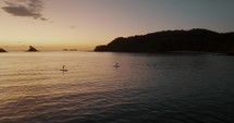 Two People Paddleboarding At Sunset In Guanacaste, Costa Rica - aerial drone shot	