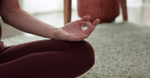 Woman meditating on living room floor - close up on hand