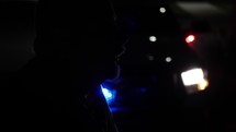 Silhouette of a criminal man in front of flashing police officer, cop car lights of law enforcement officer.