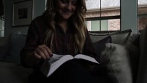 Woman sitting on a sofa, reading the Bible.