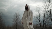 Jesus Christ in white tunic with beard after the easter resurrection in nature in Jerusalem in cinematic slow motion.