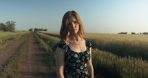 Portrait of young woman on dirt road looking at camera.