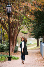 young woman walking on a sidewalk in fall 