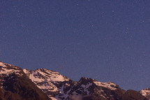 Stars above snow covered mountain peaks.