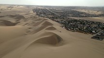 Aerial shot drone follows sand dune ridge toward Ica, Peru