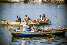 Men on row boats in the ocean water.