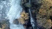 Tracking small river from overhead with ice and orange trees.