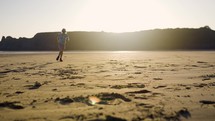Young Girl Running On The Sand On A Peaceful Beach In The Setting Sun Light