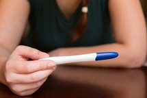 a woman looking at a pregnancy test 