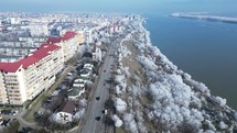Scenic Drive On Asphalt Road Through Cityscape And Winter Trees By The Danube River. Galati City In Romania. aerial shot	