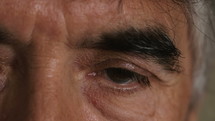 Extreme close up of a gray haired man with his eyes open.
