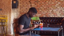 a young man sitting in a cafe using a tablet 