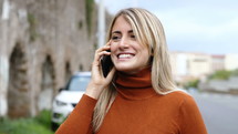 a young woman talking on a phone outdoors 