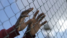 hands on a chain link fence 