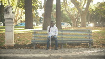 blind person sitting on a park bench 