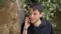 a man talking on a cellphone outdoors 