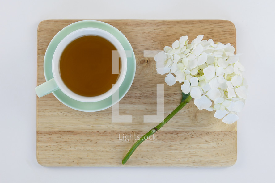 cup of tea and flowers on a wood cutting board 