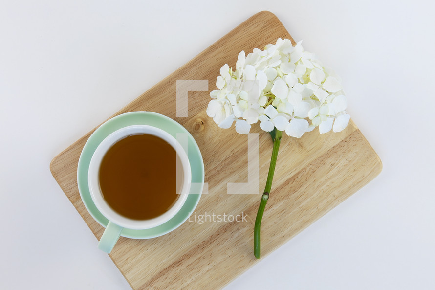 cup of tea and flowers on a cutting board 