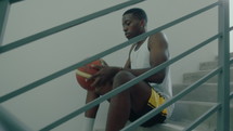  Man Sitting on Staircase and Throwing Basketball

