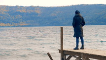 a woman standing on a dock looking out at the water 