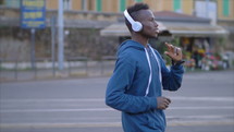 teen listening to headphones walking down a street 