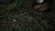 Slow motion tracking shot of the feet of Jesus Christ in white, tattered robe walking through grass in wooded area surrounded by trees.