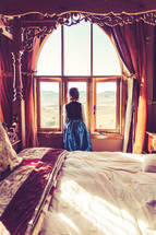 a girl dressed up like a princess looking out a window 