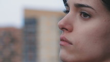 Close up side view of a woman looking off camera into the distance.