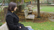a woman sitting on a park bench crying 