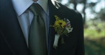 Groom, husband on wedding day wearing tux, suit and boutonniere on wedding day.