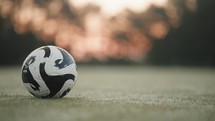 Soccer Ball Slider Shot sitting on Early Morning Field with Dew and Sunrise