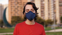 a man standing outdoors wearing a face mask 