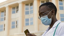 a healthcare worker wearing a mask texting 