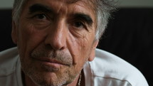 Close up of a gray haired man looking into camera.