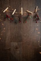 clothespins, red berries and fairy lights on a wood background 