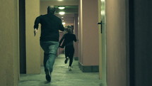 Man chasing a woman down a hallway.