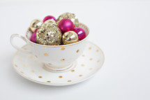 gold and fuchsia ornaments in a tea cup 