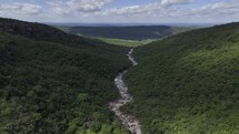 Drone flies out of valley with river cutting through middle