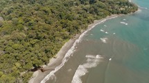 Aerial birds eye shot of beautiful tropical ocean shore beside green trees in Costa Rica - Waves of Caribbean Sea reaching beach