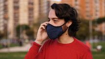 a man in a face mask talking on a cellphone 