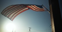 American flag blowing in wind in slow motion in light of sunset.