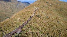 Aerial shot drone orbiting solo hiker descending mountain