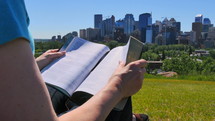 woman reading a Bible in a city park 