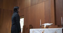 Young man looking at wooden cross in church.