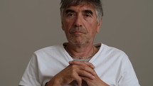 Gray haired man staring into camera.
