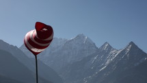 Windsock blowing in wind with Himalaya Mountain peaks in background