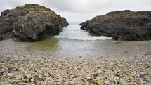 Pebbles And Coastal Rocks With Waves Slowly Crashing Slow Motion